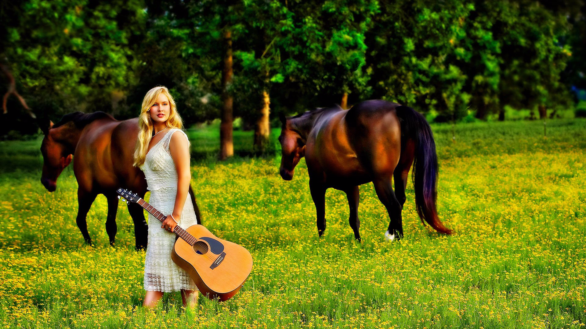 A woman in a white dress is holding a guitar in a field with two horses.