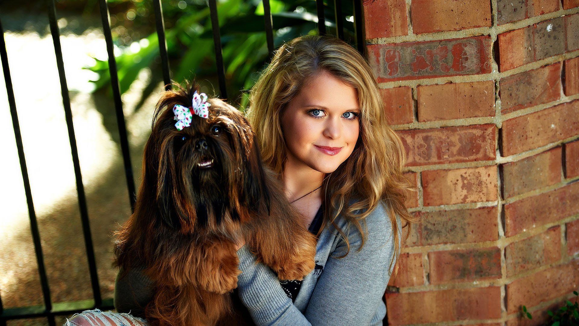 A woman is sitting next to a small brown dog.
