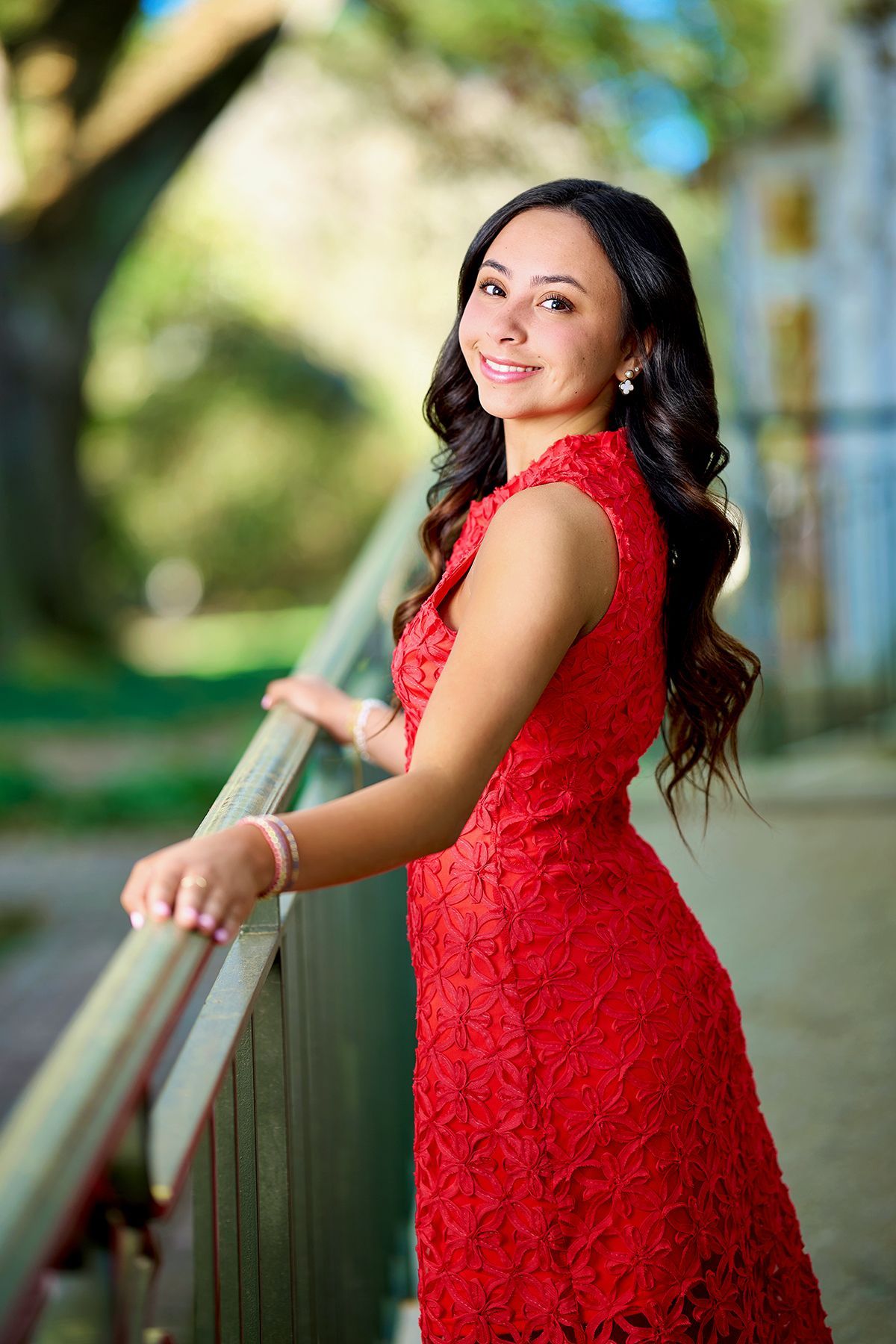 A woman in a grey dress is standing in front of a tree with red leaves.