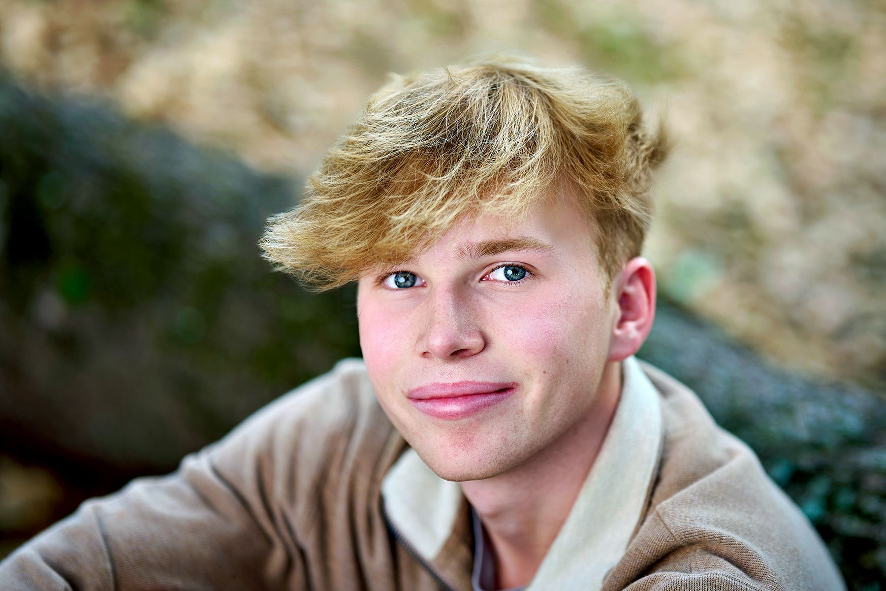 A young woman in a red shirt is leaning on a railing and smiling.