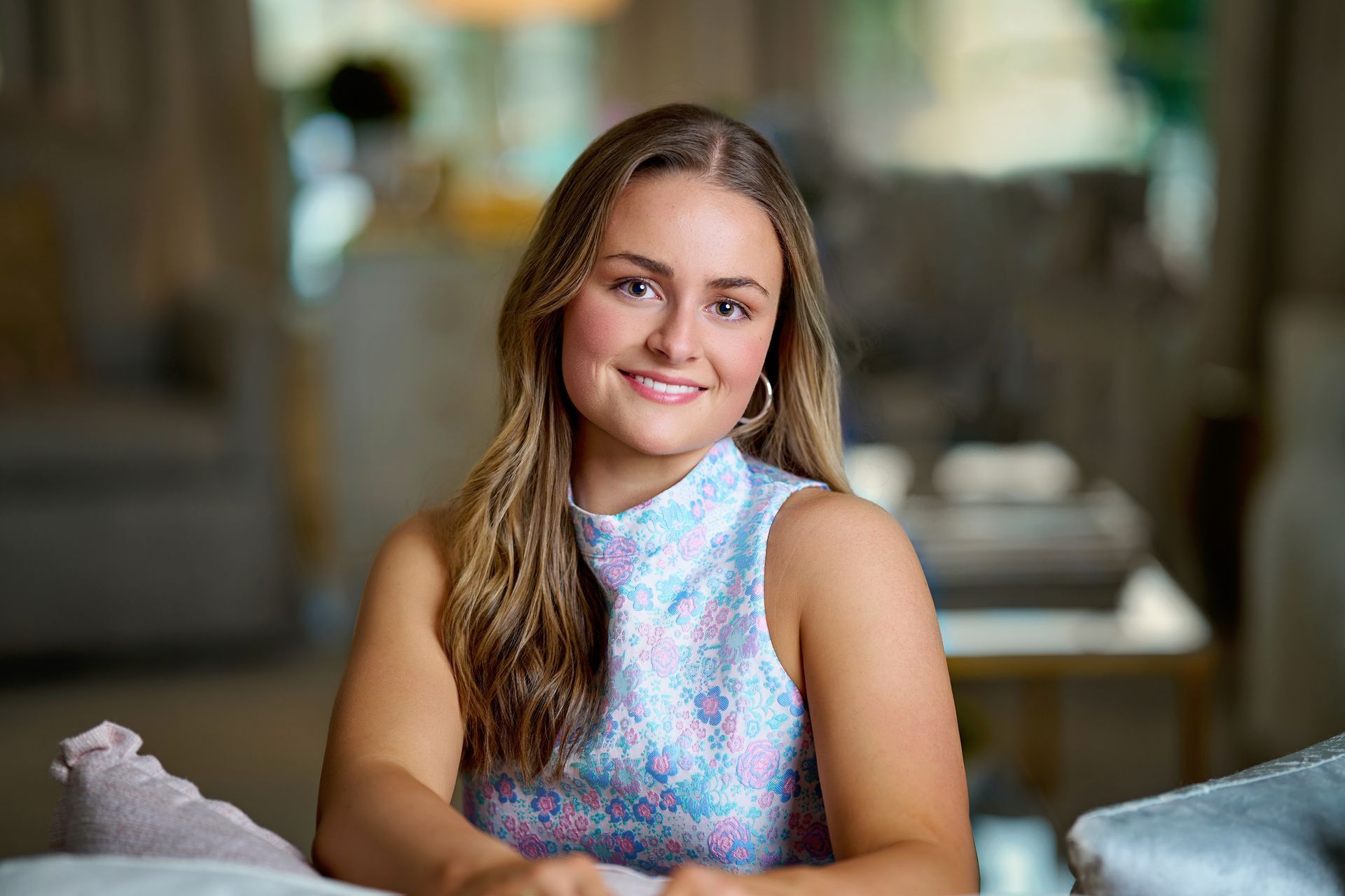 A young woman wearing a red and black letterman jacket is sitting on a tree branch.