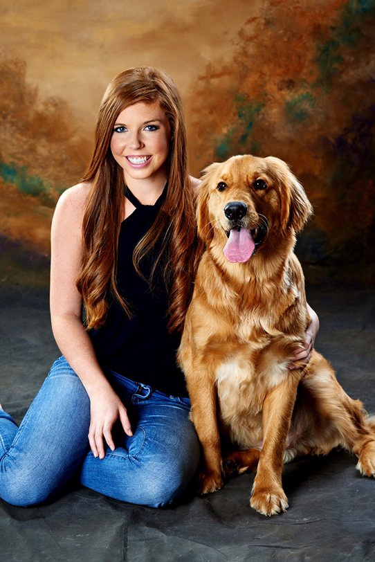 A woman is kneeling down next to a dog.
