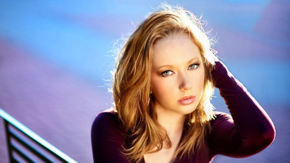 A woman is standing on a set of stairs with her hand in her hair.