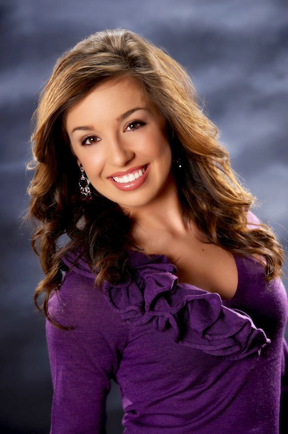 A woman in a purple dress is smiling for the camera