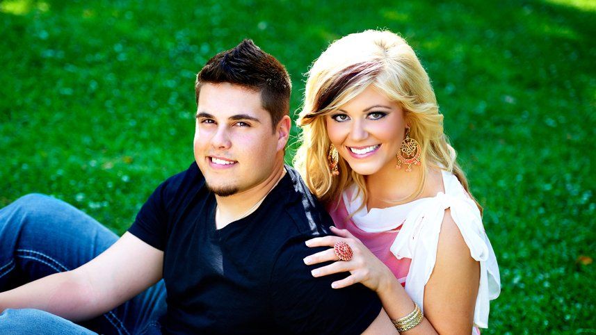 A man and a woman are posing for a picture in the grass.
