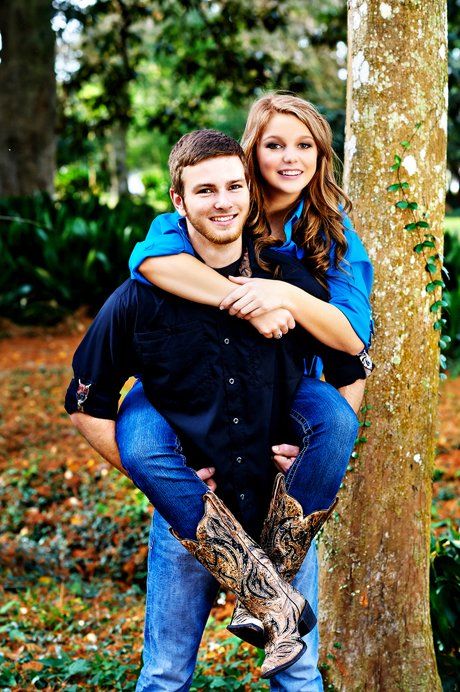 A man is carrying a woman on his back in front of a tree.