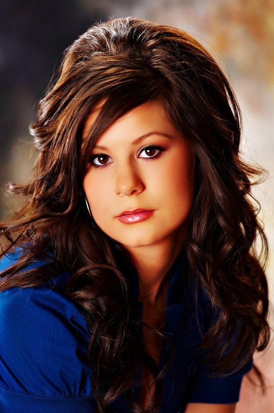 A woman with long brown hair is wearing a blue shirt