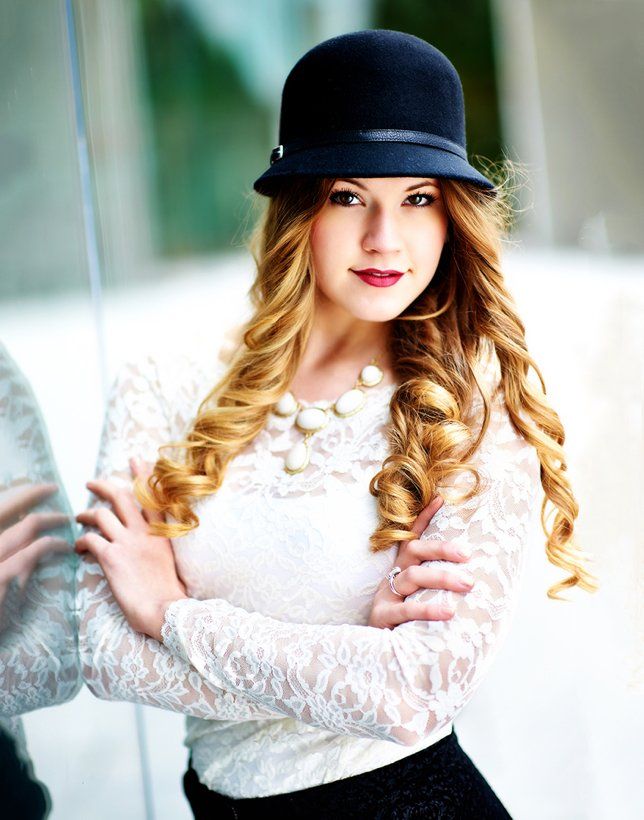 A woman wearing a black hat and a white top