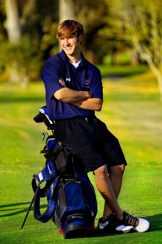 A young man leaning on a golf bag on a golf course