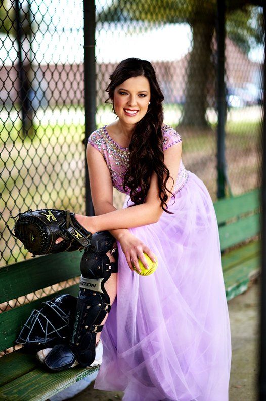 A woman in a purple dress is sitting on a bench holding a baseball.