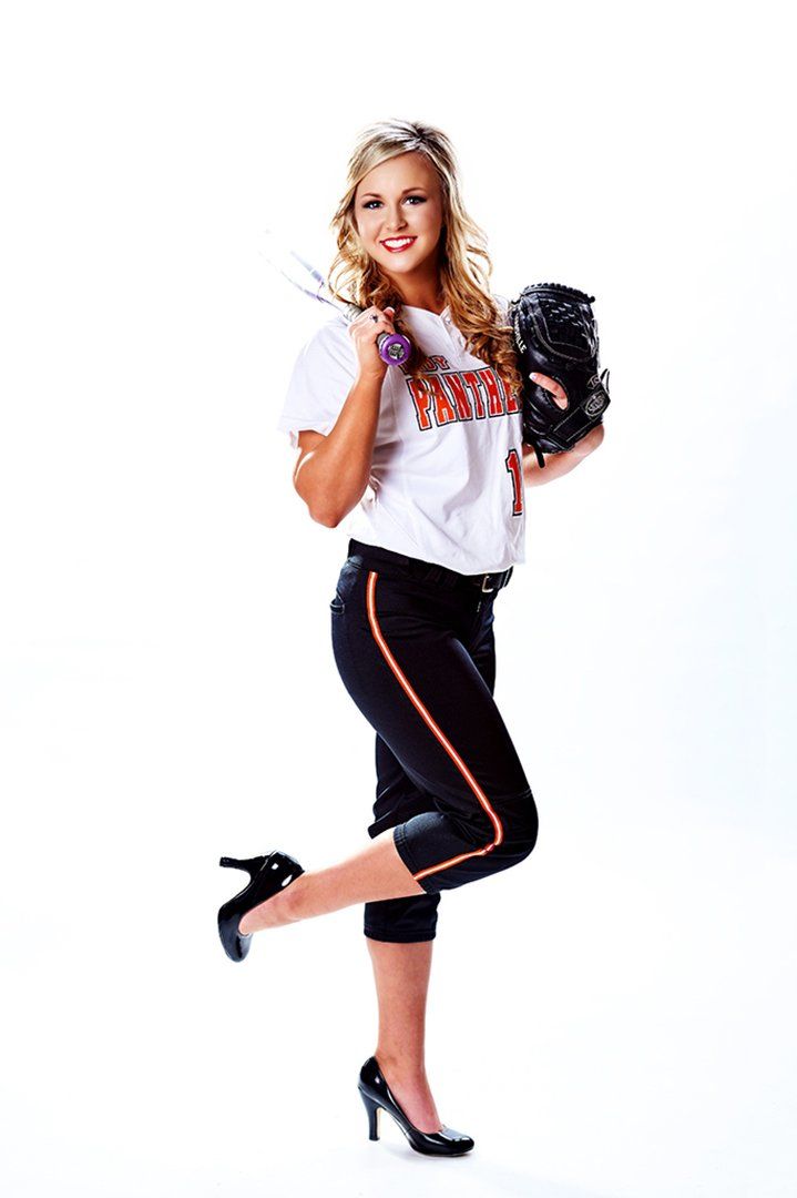 A woman in a softball uniform is holding a baseball glove