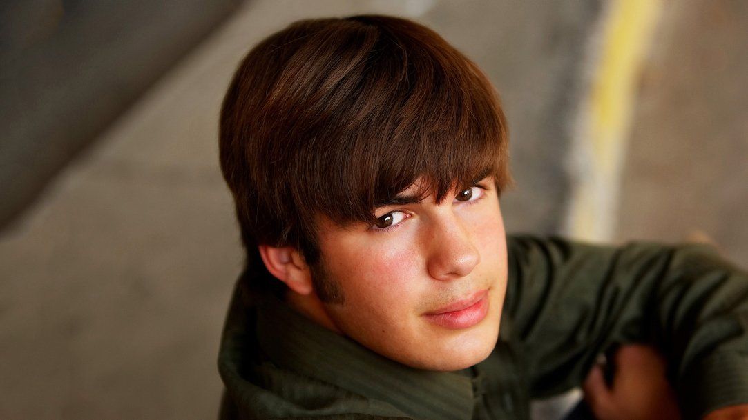 A young boy is sitting on the ground and looking at the camera.