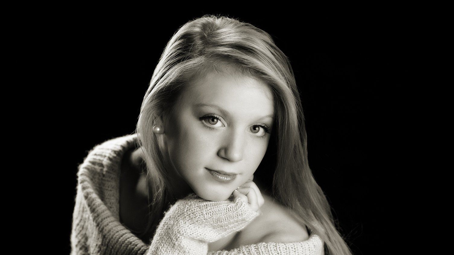 A black and white photo of a woman wearing a sweater.