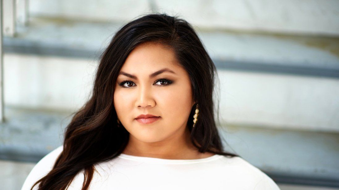 A woman in a white shirt is standing in front of a set of stairs.