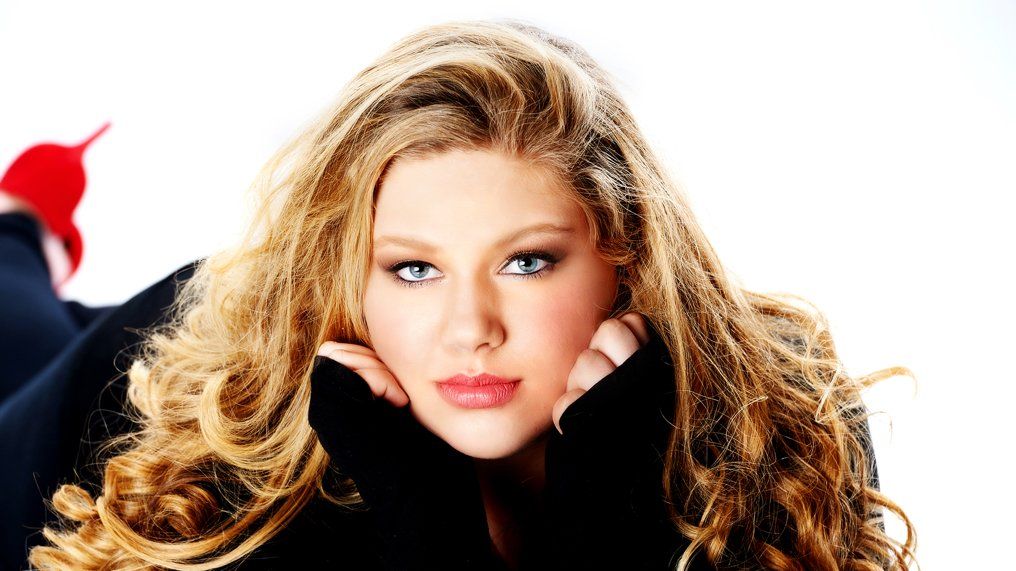 A woman with long blonde hair is wearing a black sweater