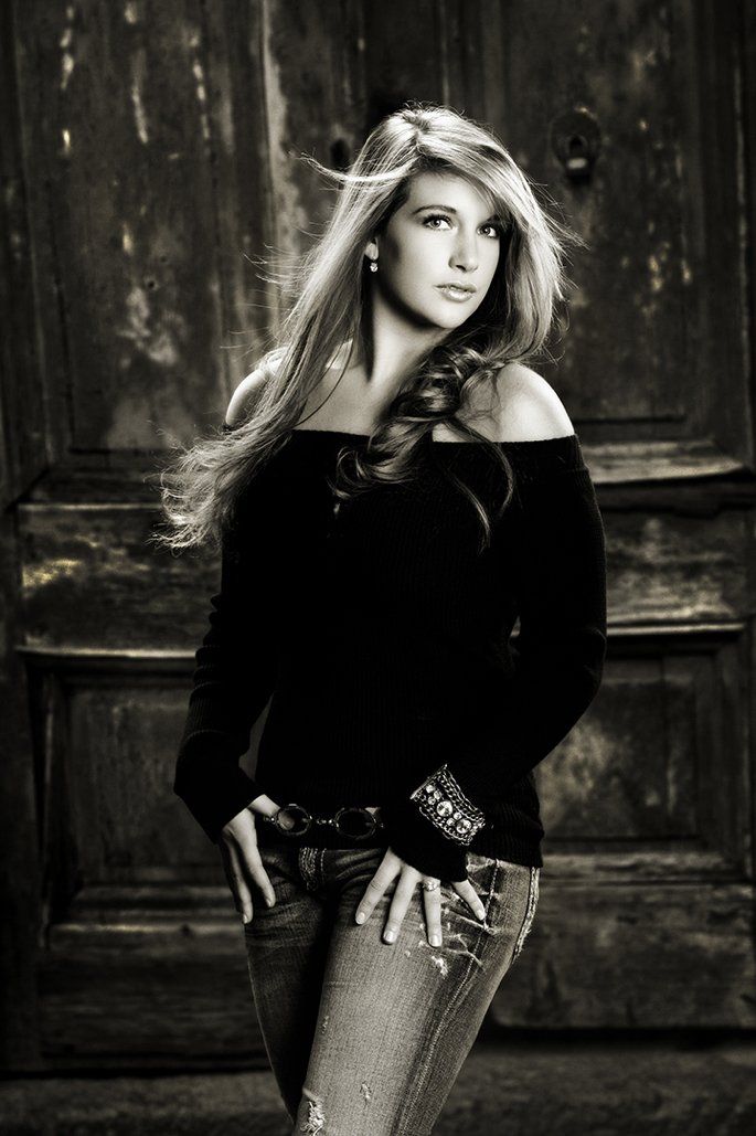 A black and white photo of a woman standing in front of a door