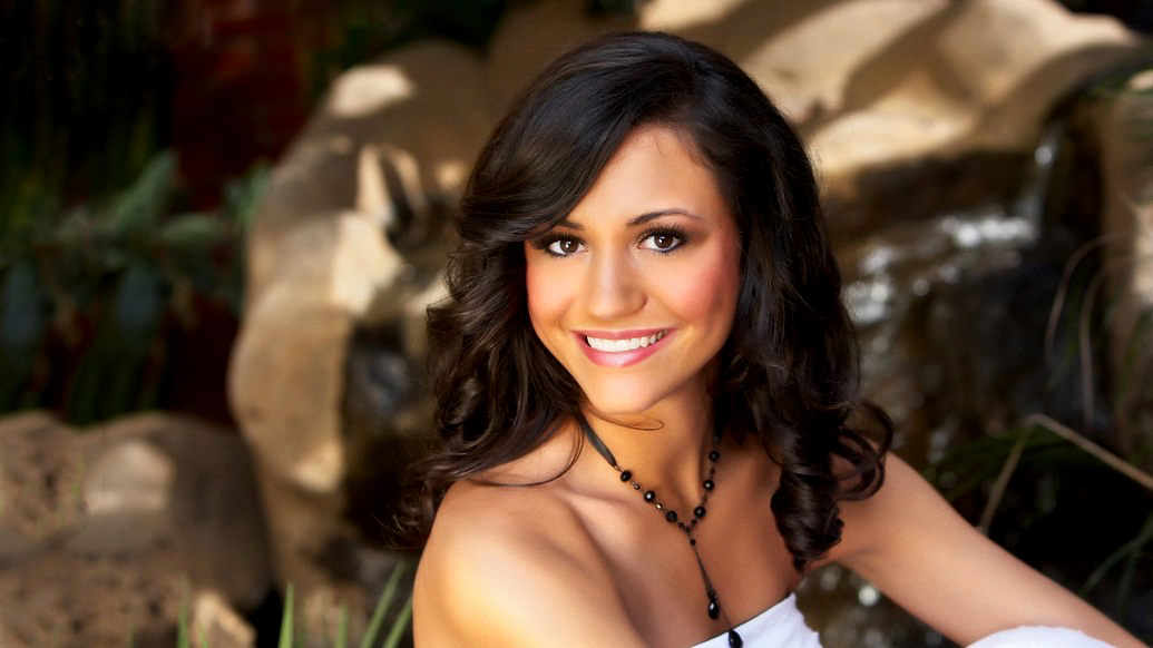 A woman in a white dress is smiling for the camera