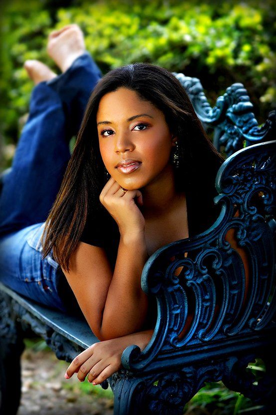 A young woman is laying on a blue bench with her feet up.
