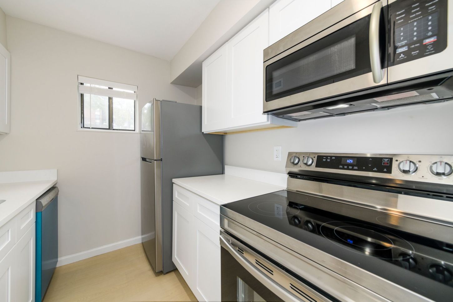 Kitchen with white cabinets, stainless steel appliances, and a small window.