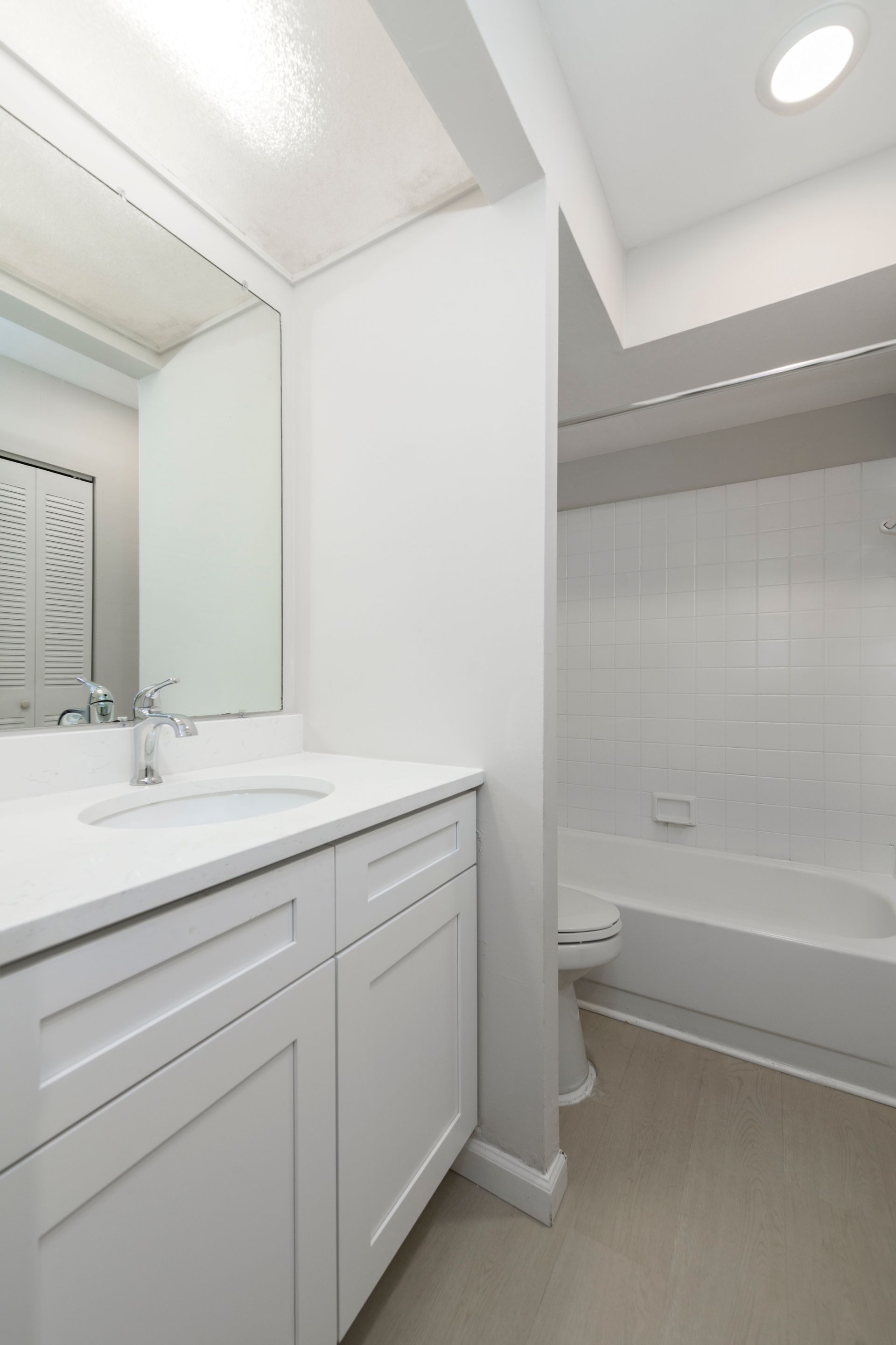 White bathroom with sink, vanity, toilet, and bathtub.