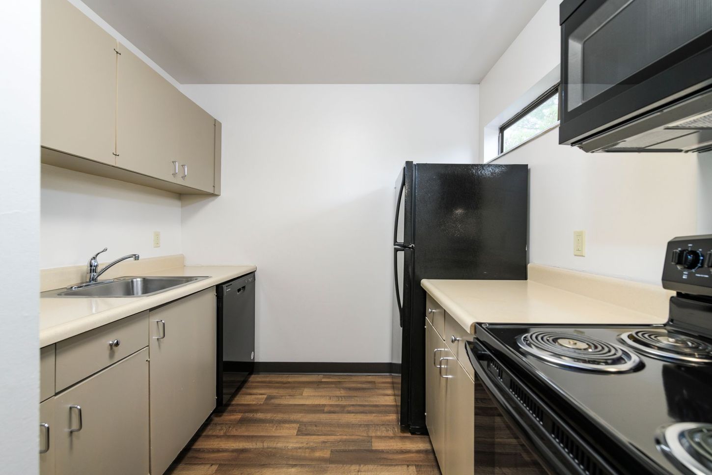 Kitchen with beige cabinets, black appliances, and light countertops.