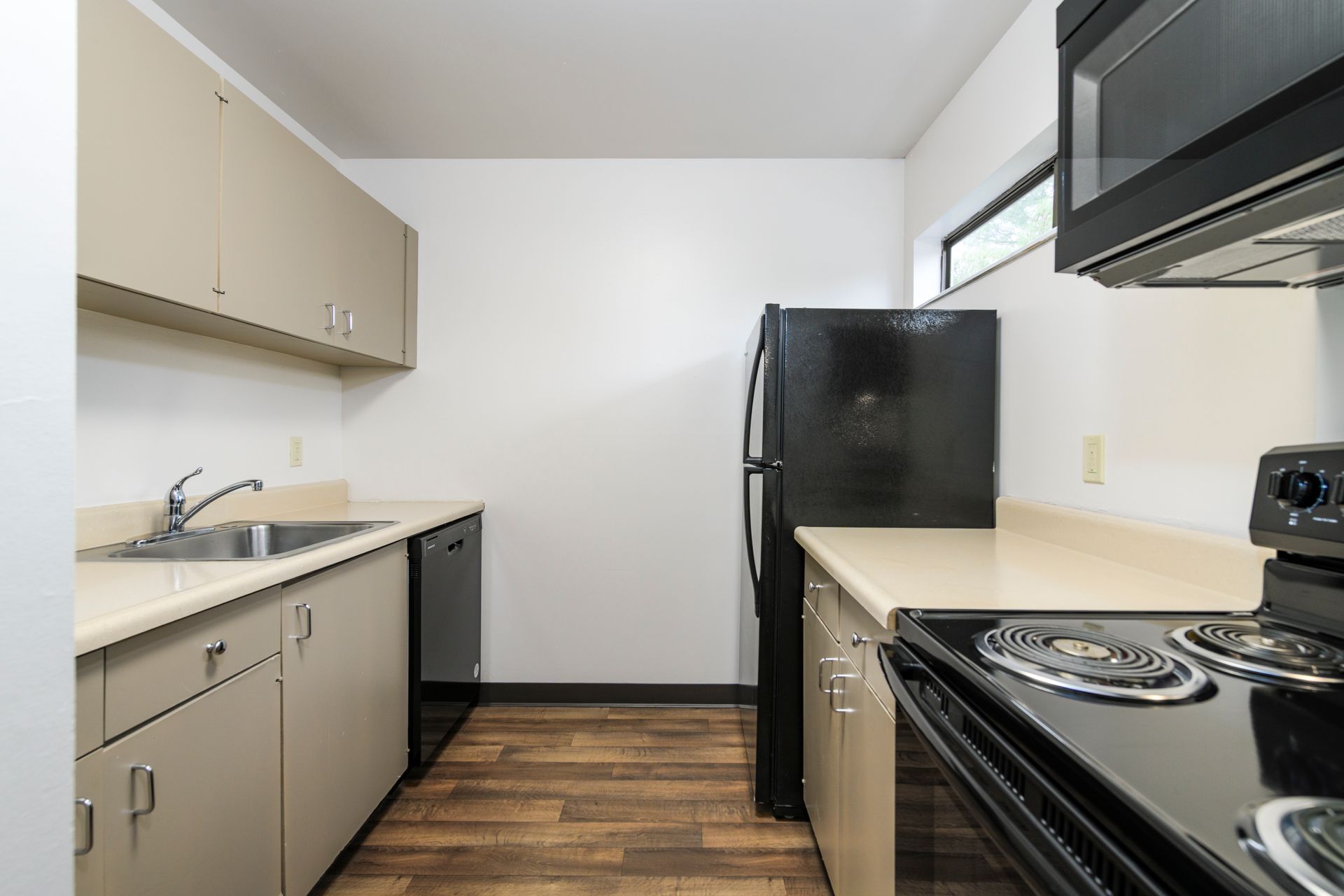 Kitchen with beige cabinets, black appliances, and light countertops.