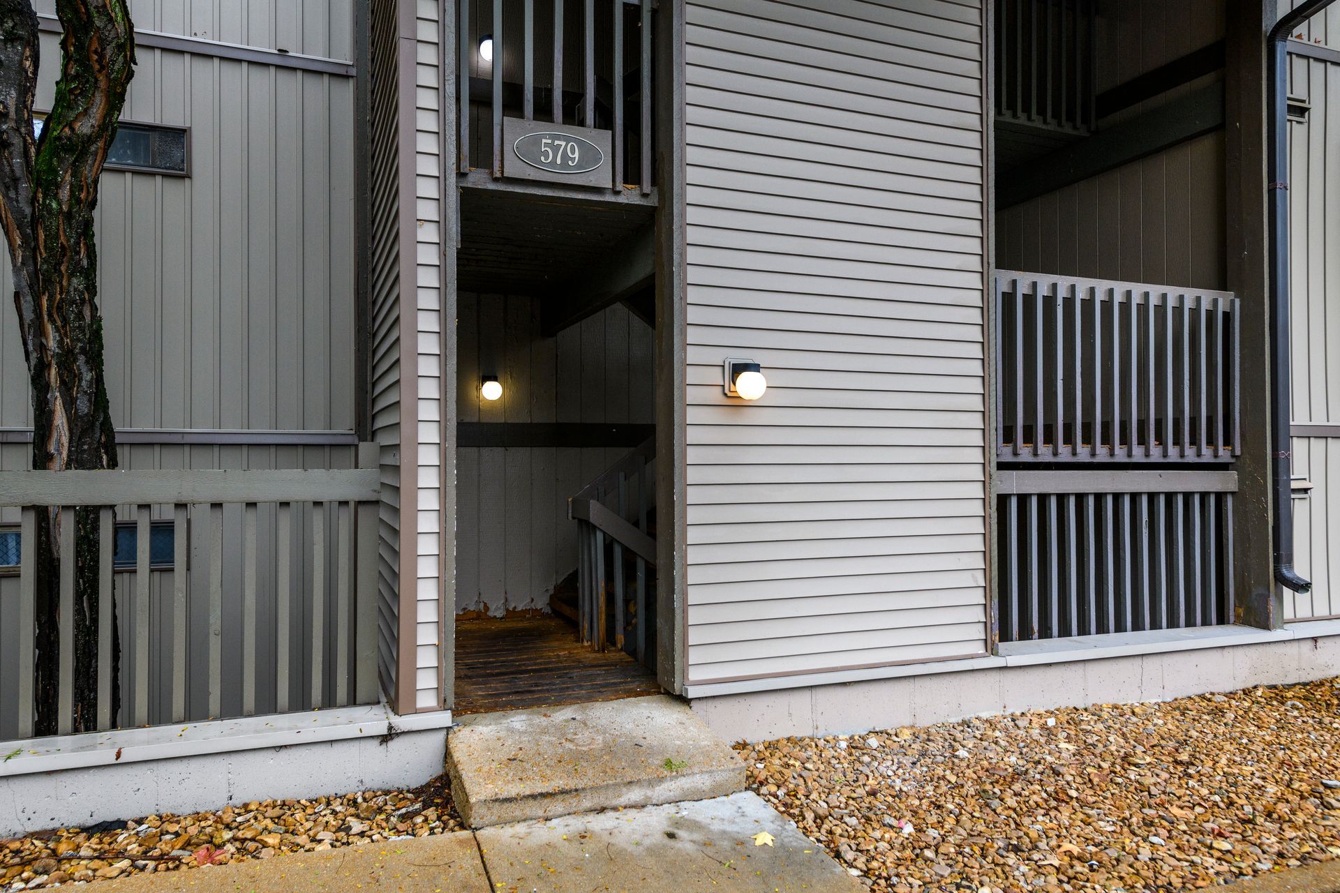 Exterior of an apartment building entrance with a staircase and wooden railings.