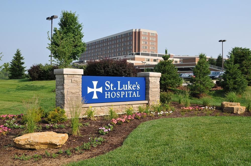 A sign for st. luke 's hospital is in front of a large building
