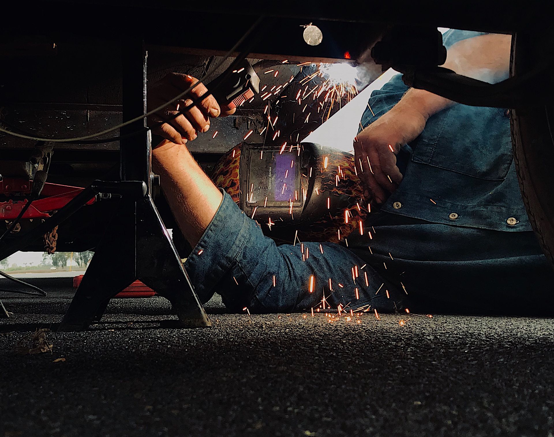A man is welding under a car on a jack.