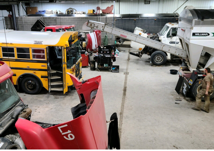 A yellow school bus is being worked on in a garage