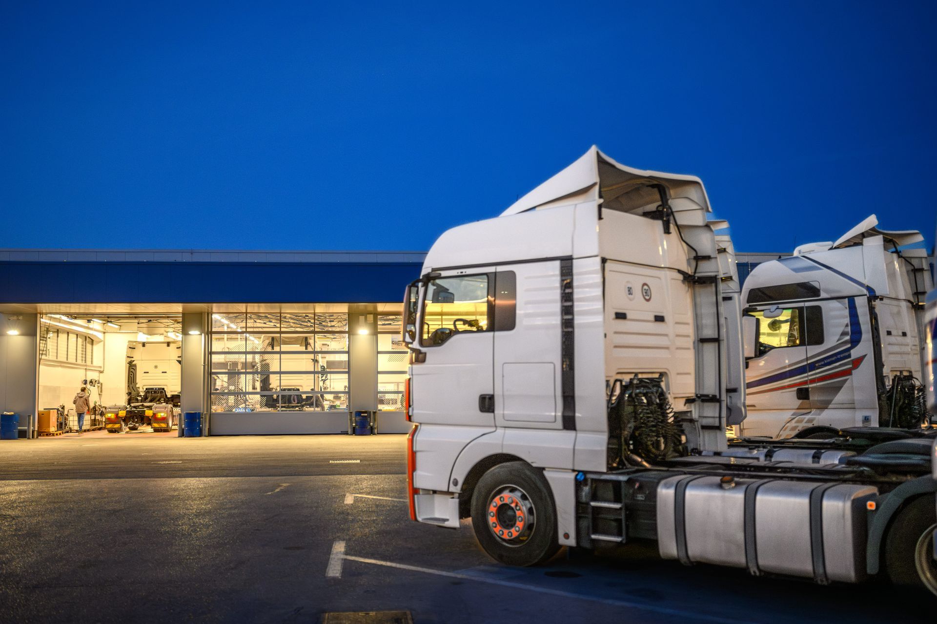 Exterior of truck repair shop at night with a truck parked outside.