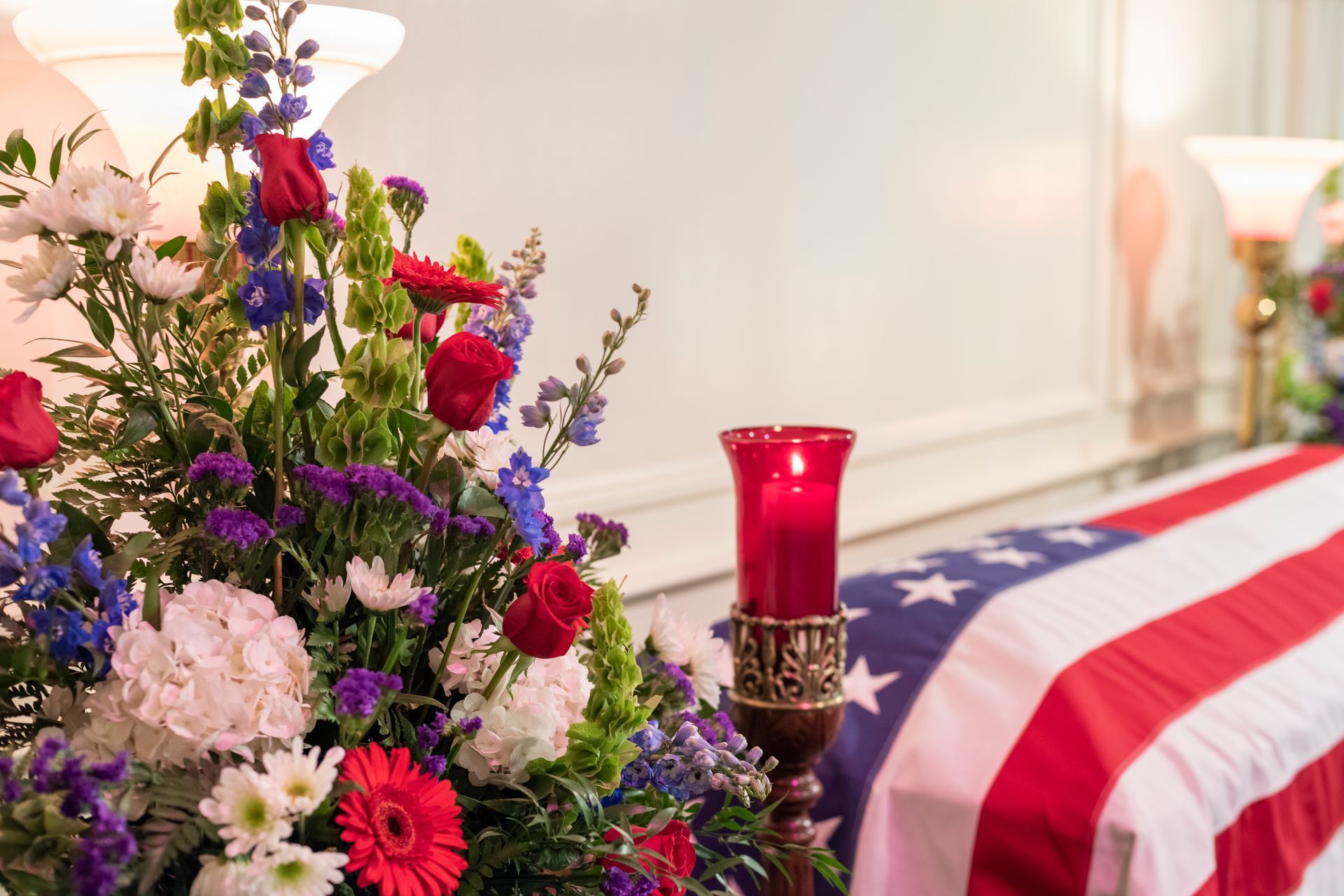 A woman is holding an american flag and a rose at a funeral.