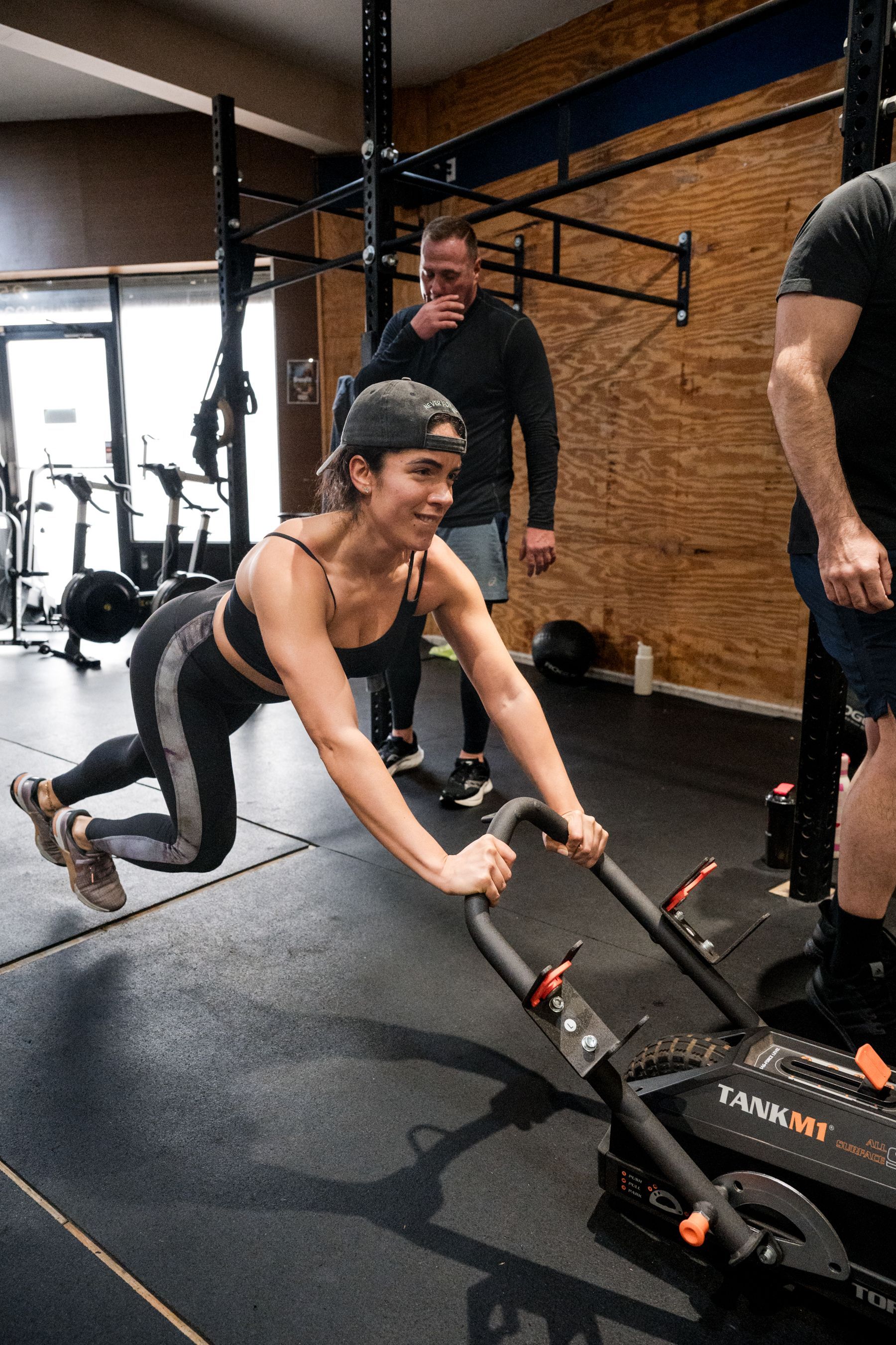 A woman is doing push ups on a machine in a gym.