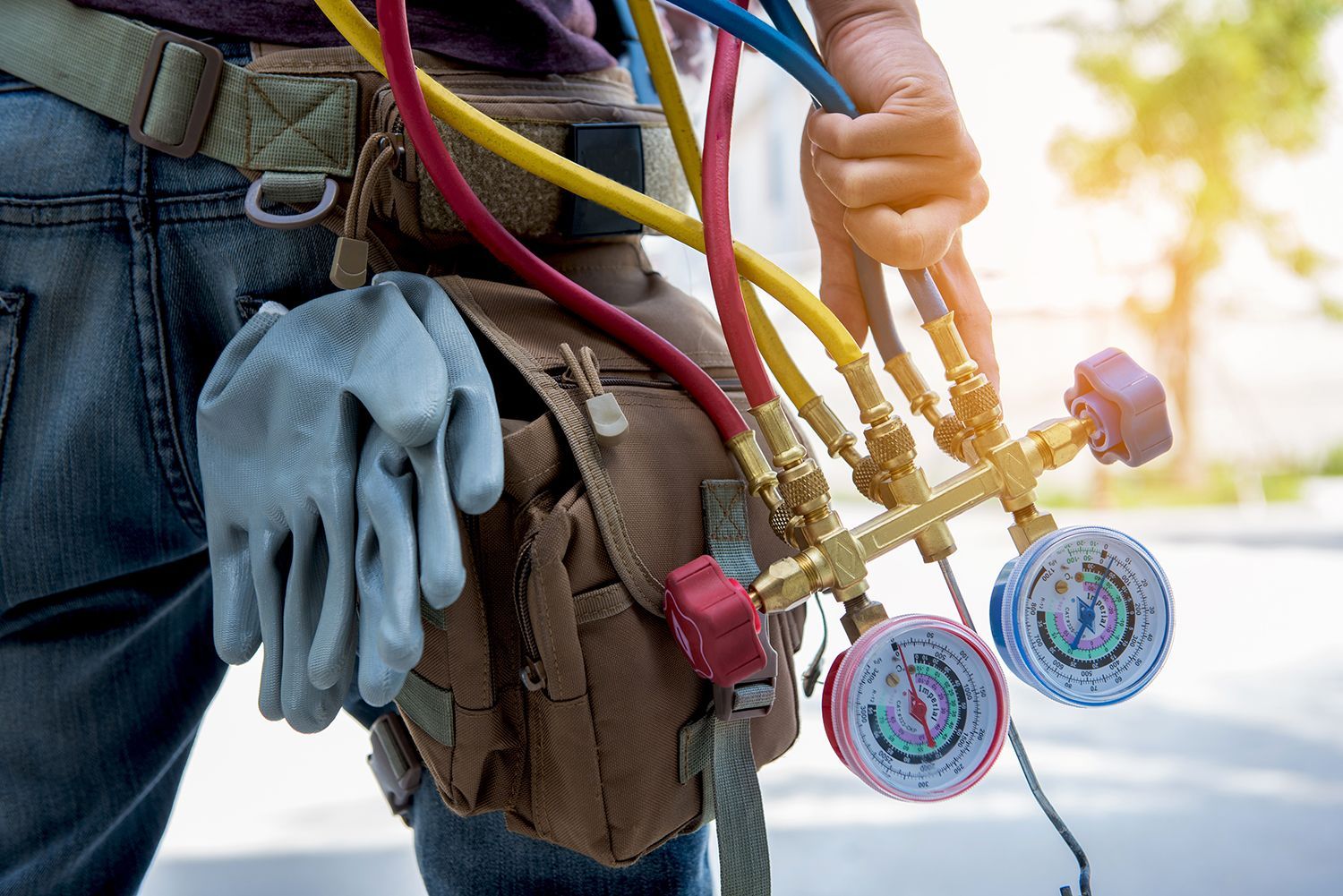 Closeup at a HVAC technician’s hand with HVAC valves and blue gloves in the sides.