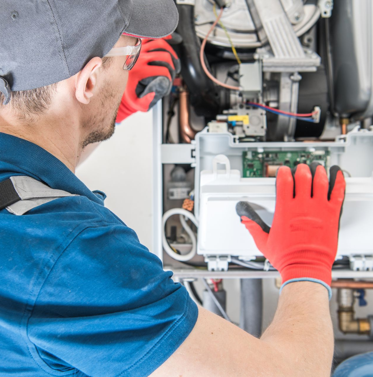 Technician servicing a gas boiler, inspecting internal components during maintenance.