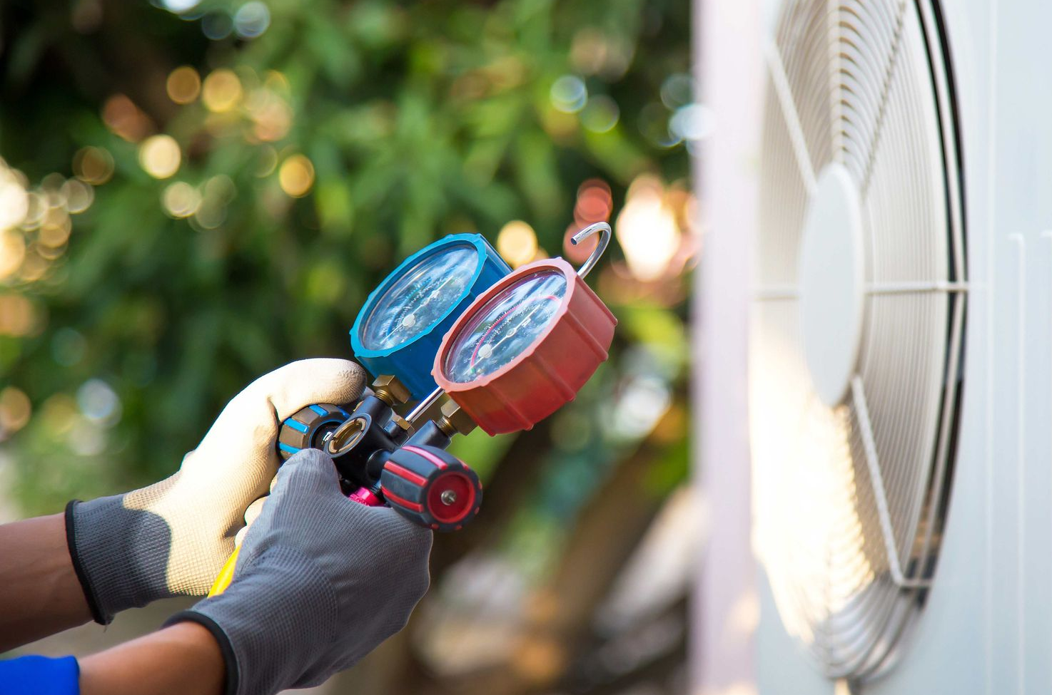 HVAC technician using a manifold gauge to check an air unit.