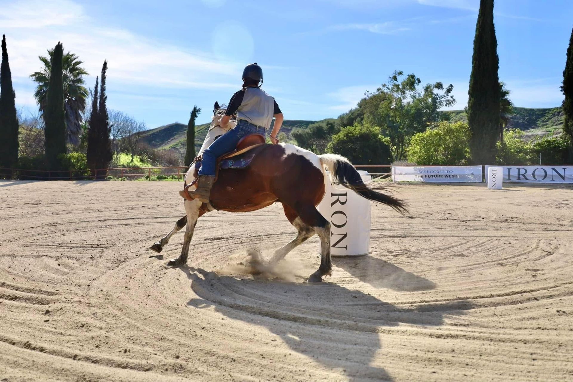 A rider and a paint horse turning around a barrel at a local barrel racing event, exemplifying the sport's dynamic and competitive nature.