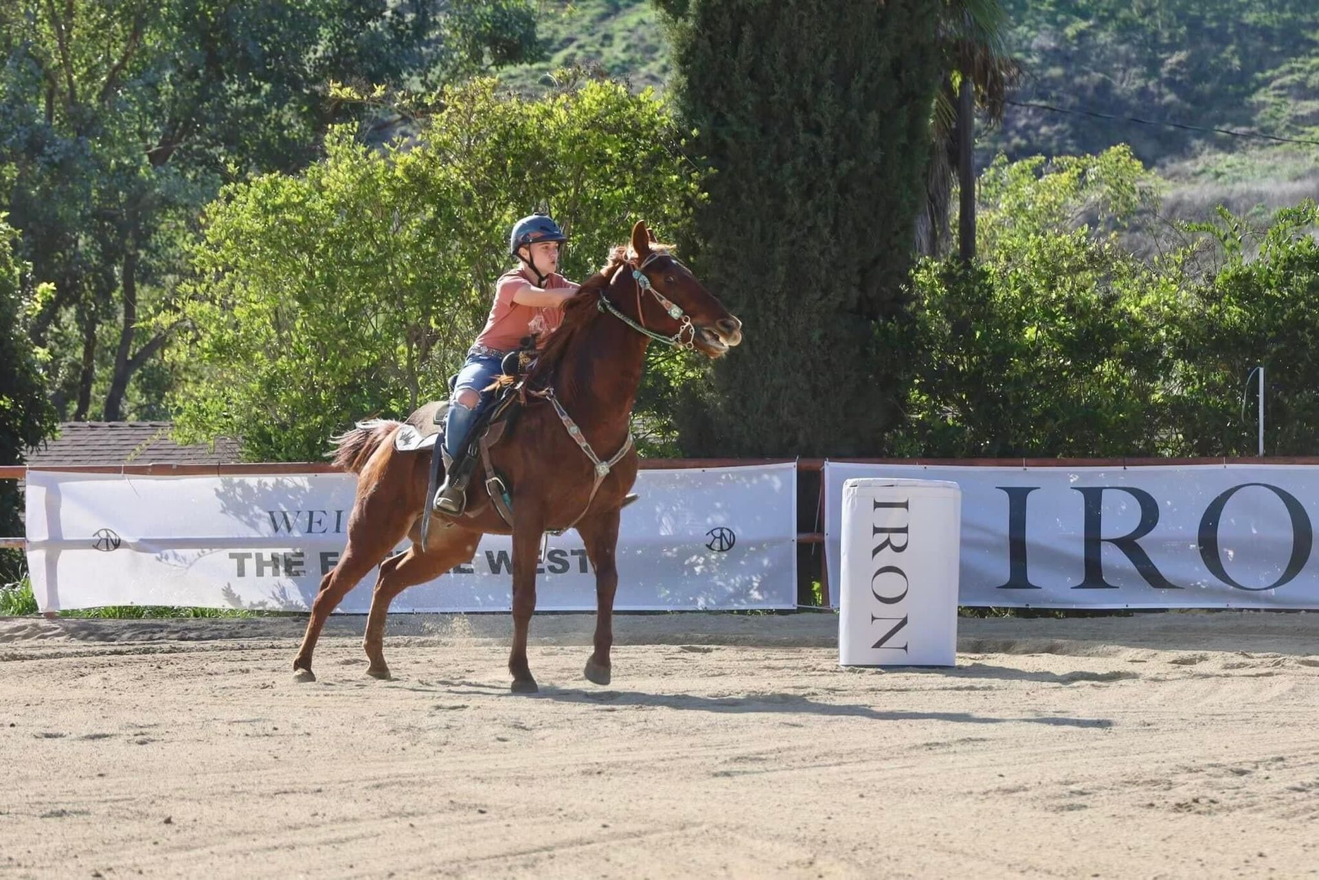 Competitor engaging in barrel racing at a local event, demonstrating horse riding skill and speed in a dusty arena.