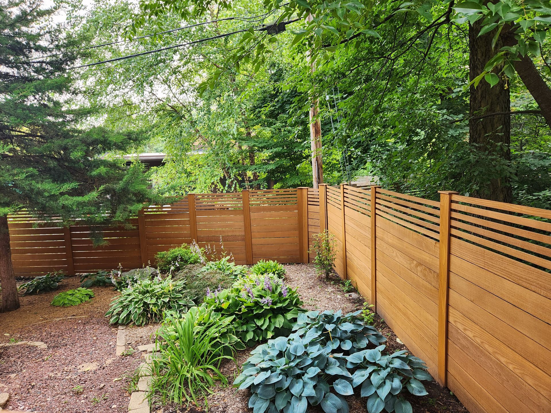 A man is painting the side of a building with a ladder.