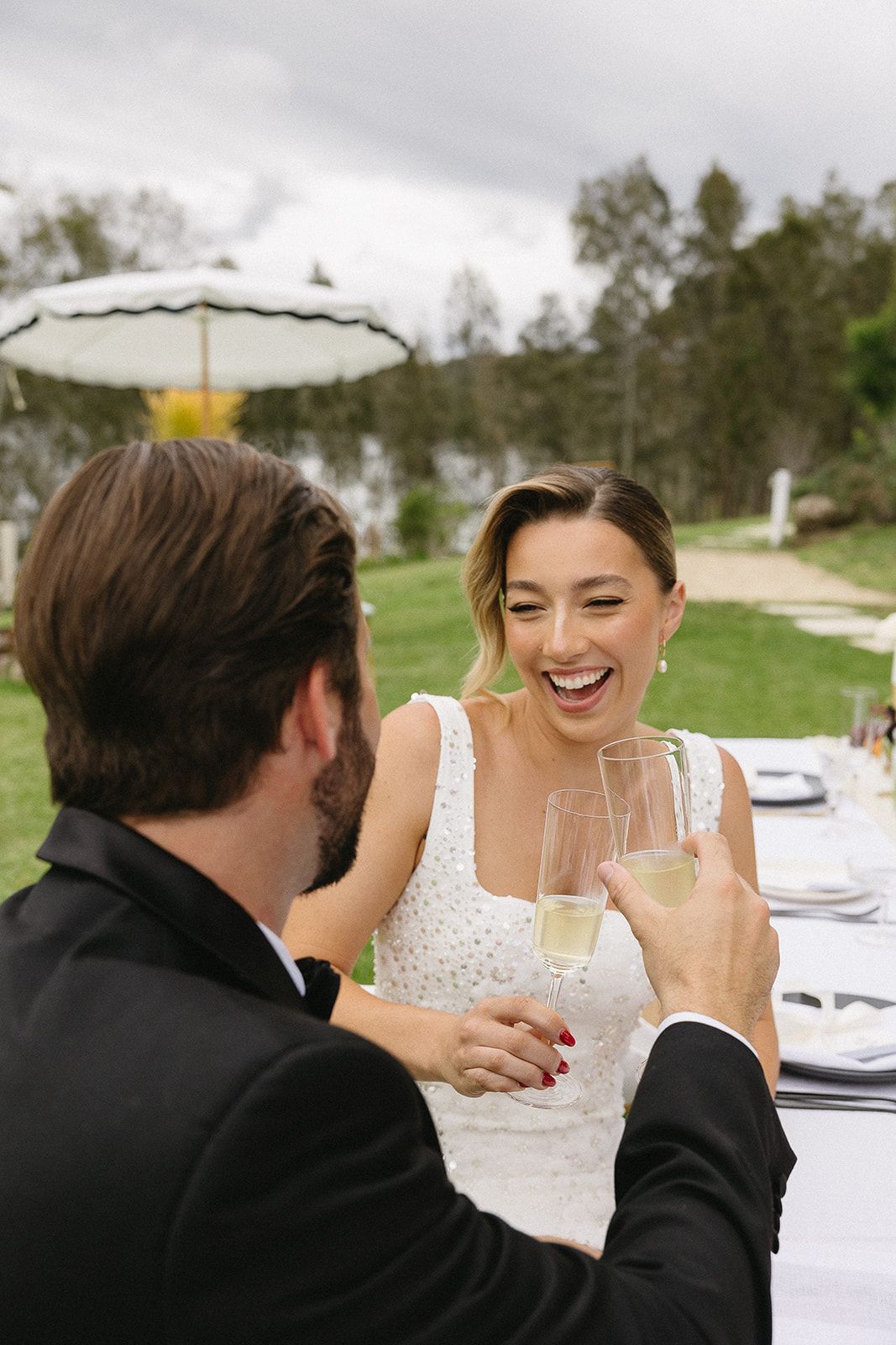 A bride and groom are toasting with champagne at their wedding reception.