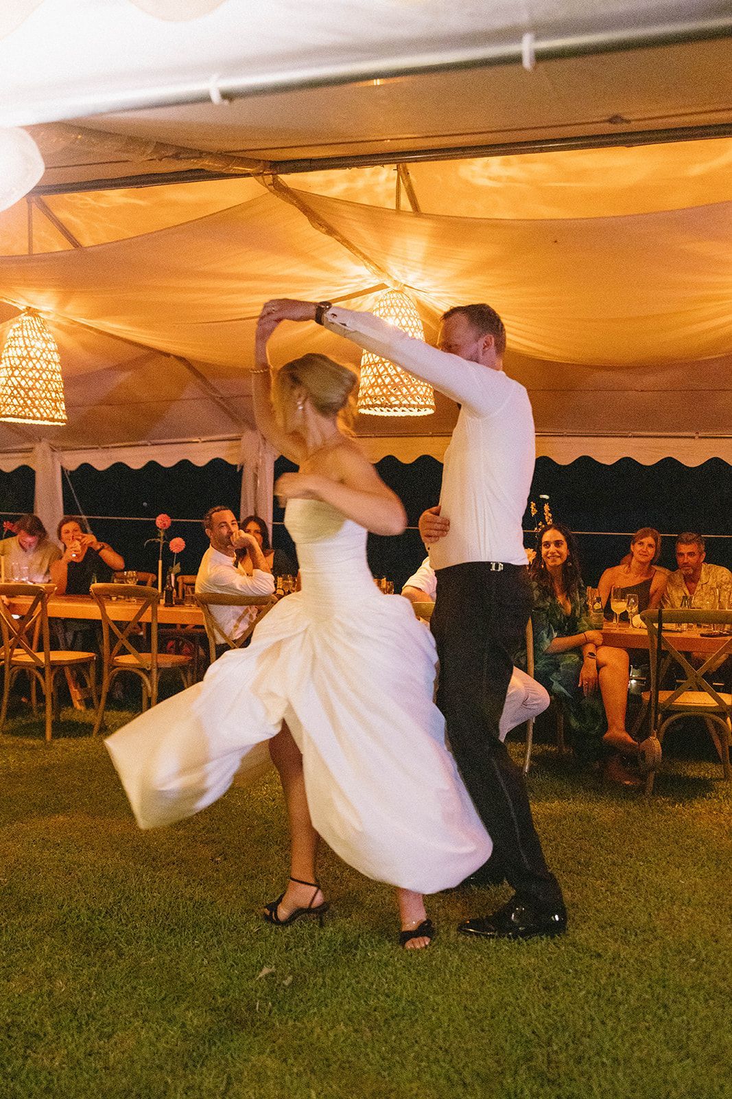 A bride and groom are dancing under a tent at their wedding reception.