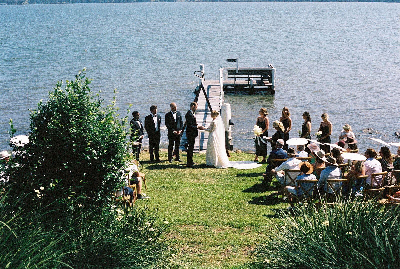A bride and groom are getting married in front of a lake.