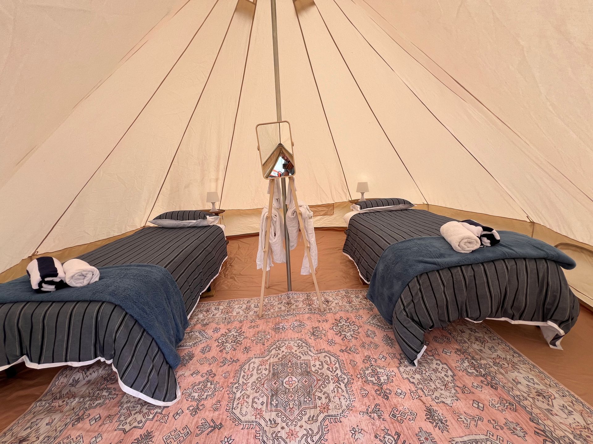 A tent with two beds and a rug on the floor.