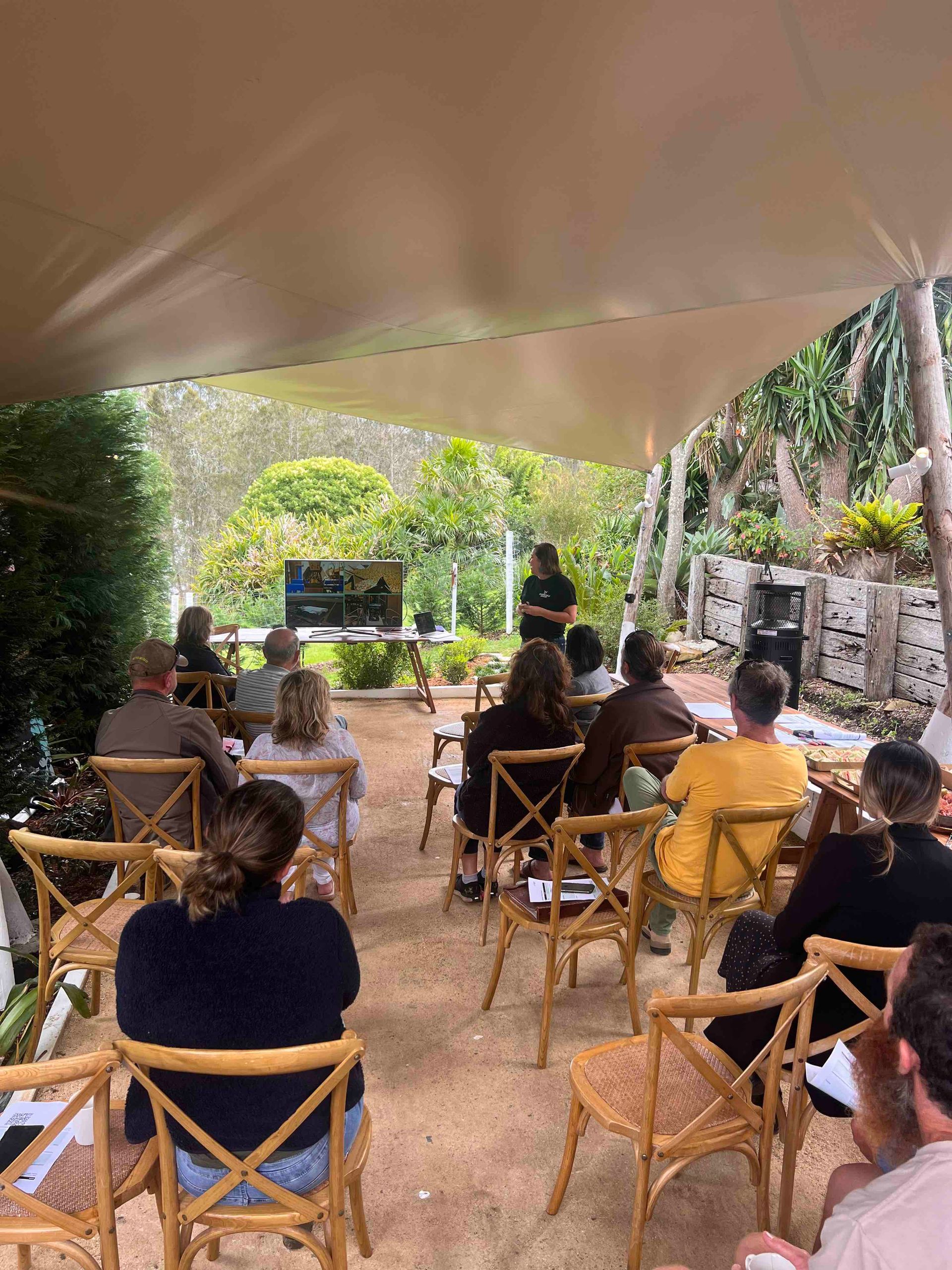 A group of people are sitting in chairs under a tent.