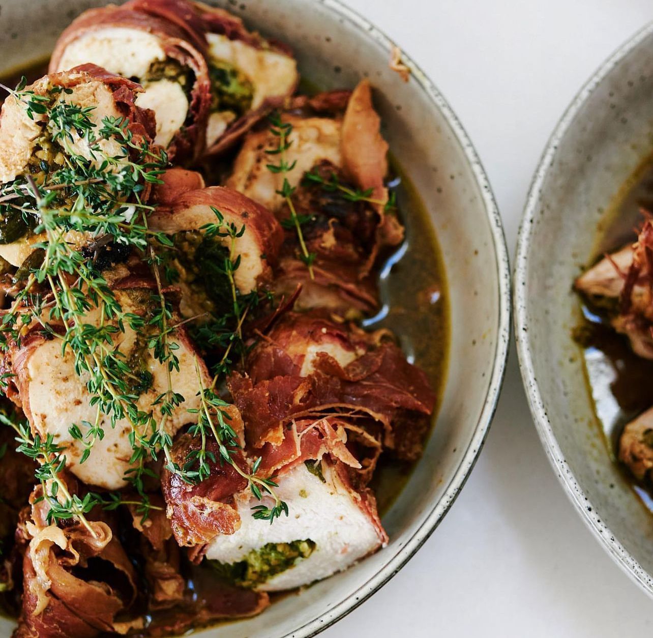 Two bowls of food with meat and vegetables on a table
