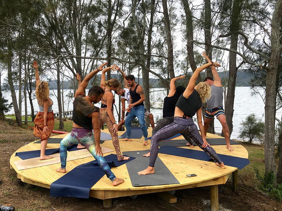 A group of people are doing yoga on a wooden platform.