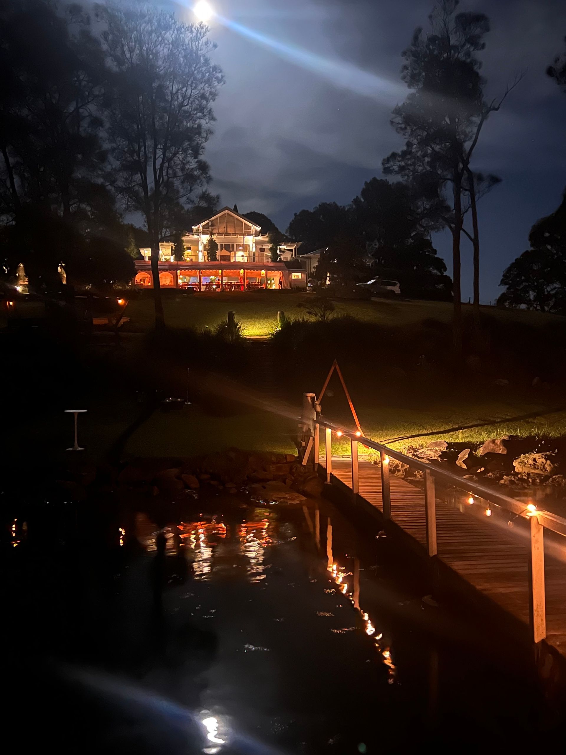 A large house is lit up at night with a dock in front of it