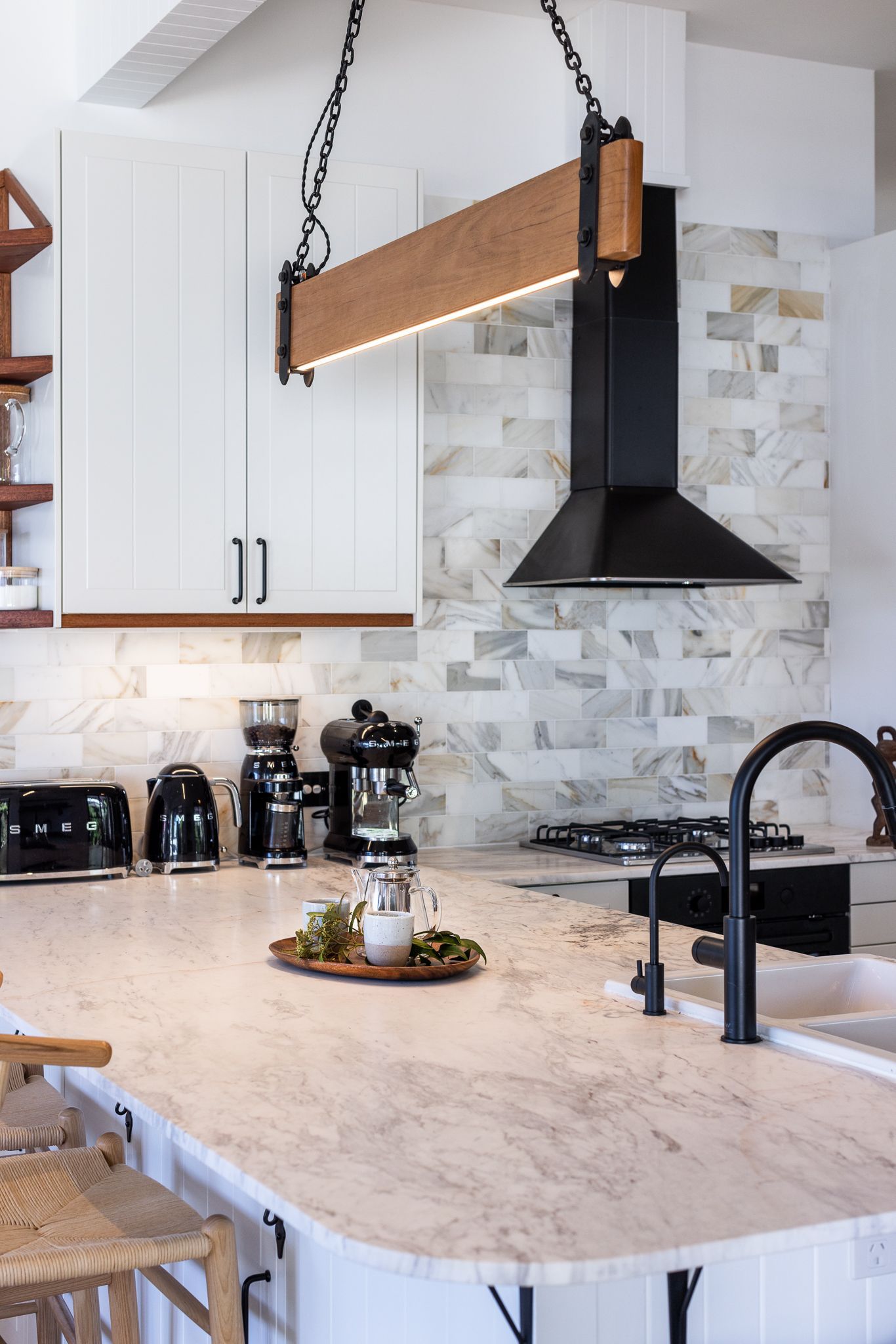 A kitchen with white cabinets , a sink , a stove and a hood.