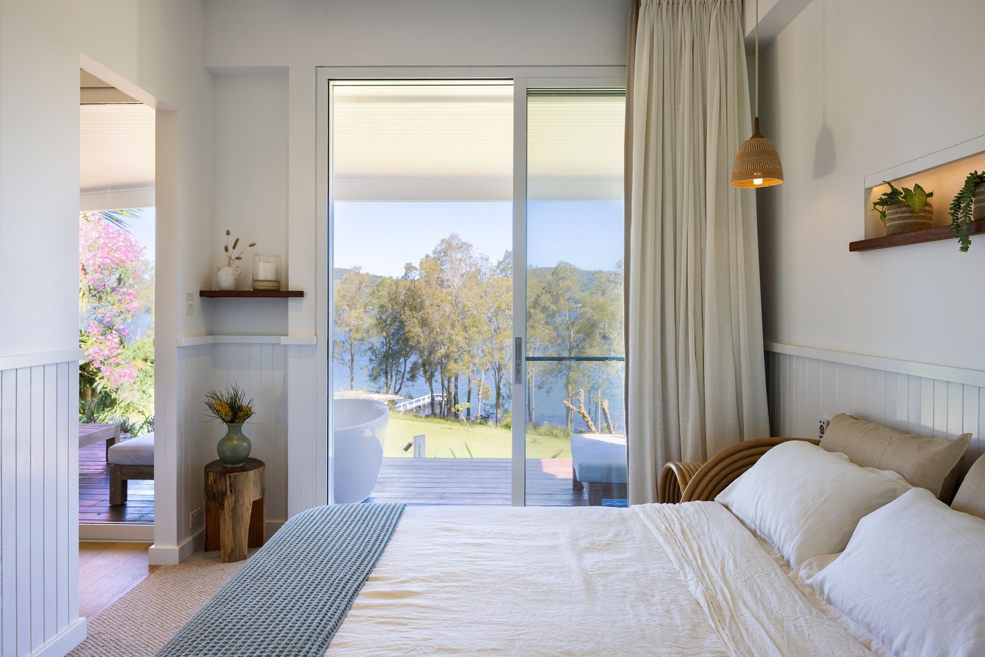 A bedroom with a large bed and a sliding glass door leading to a balcony.