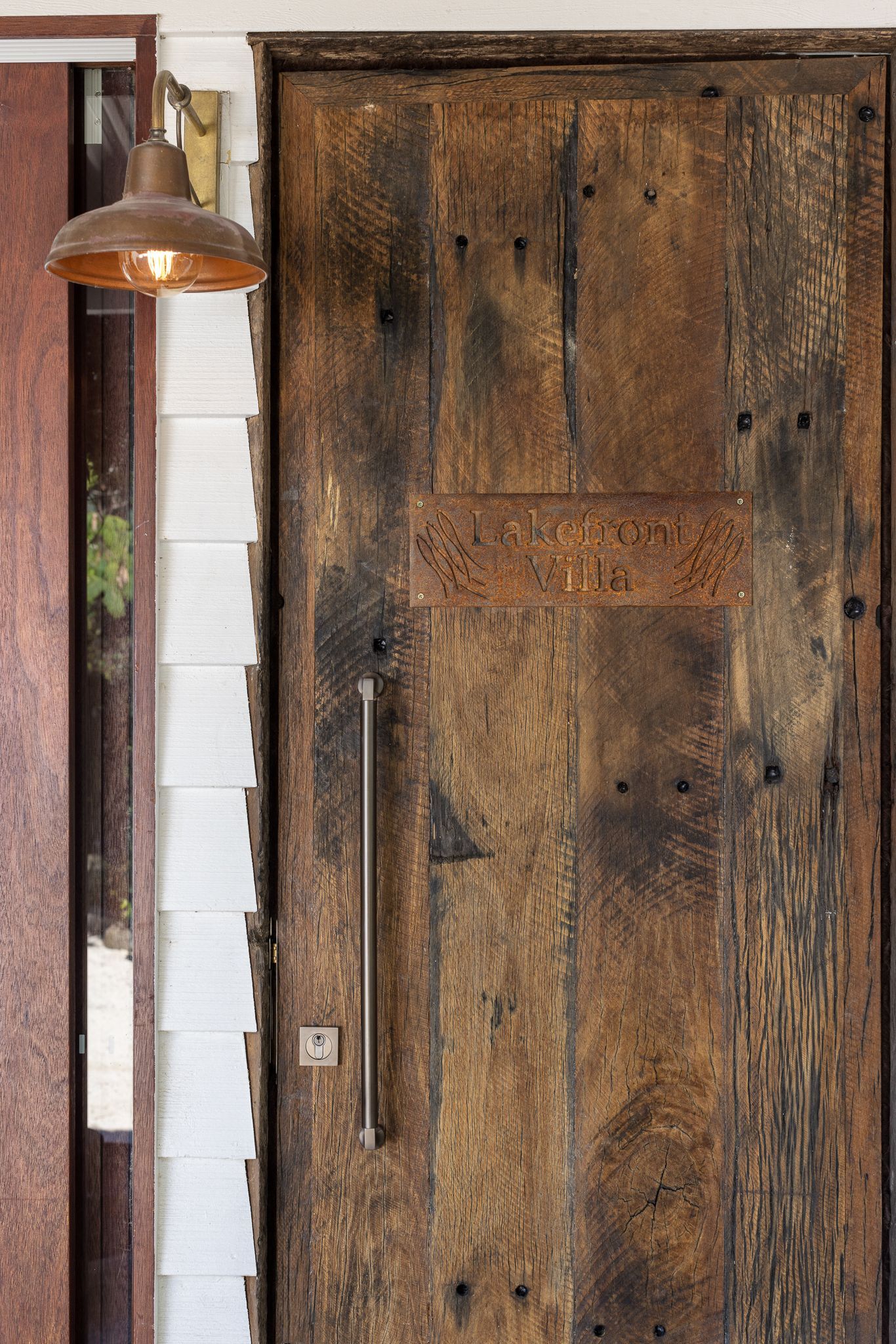A close up of a wooden door with a light hanging from it.